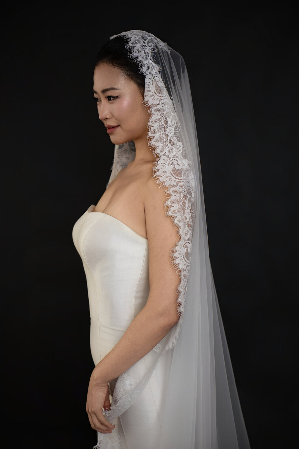 Profile view of The Close Up mantilla veil showing the scalloped lace border framing the face and shoulder