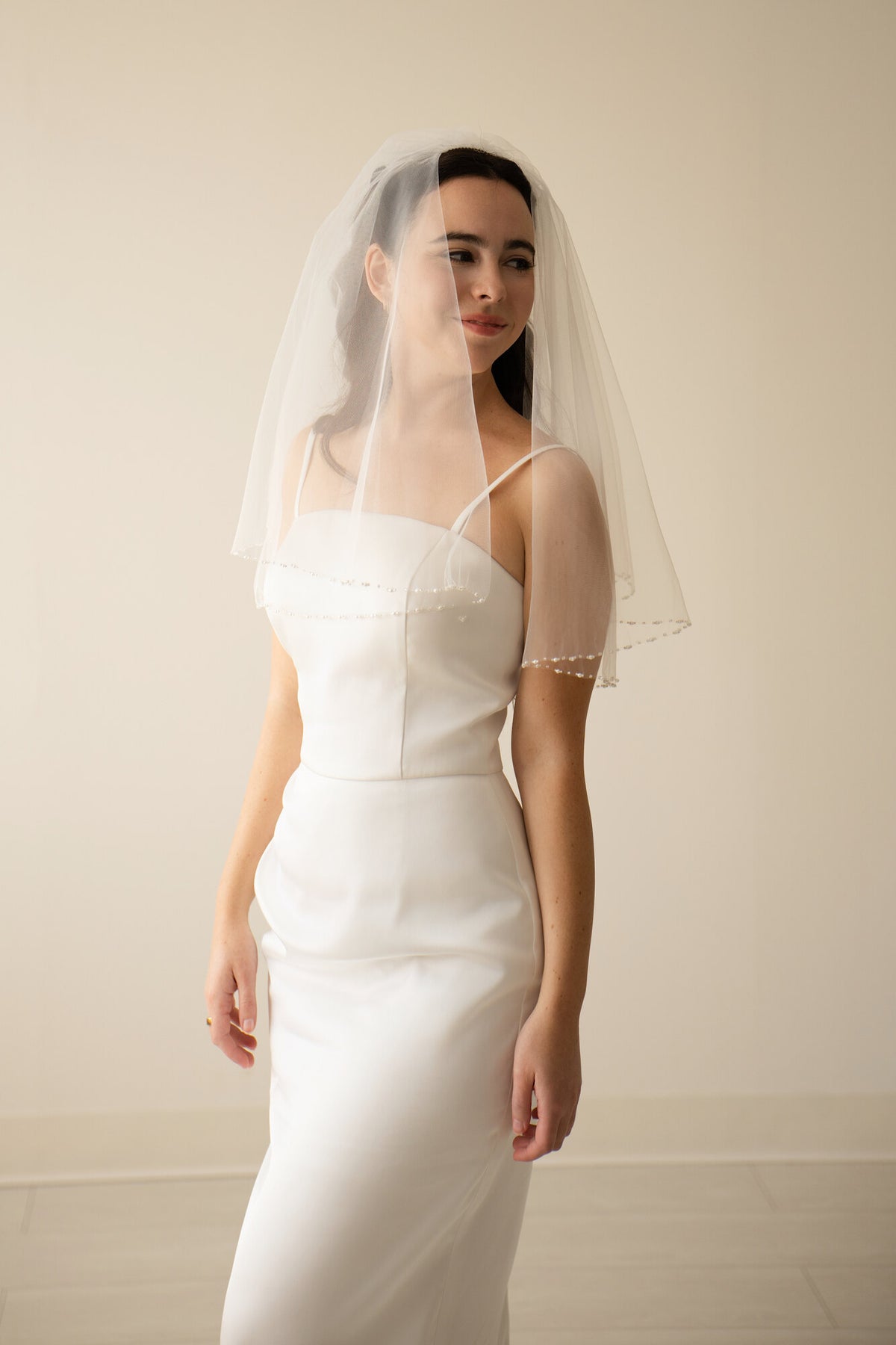 Three quarter view of The Second Look shoulder length veil showing the beaded pearl edge along both tiers