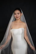 Front view of The Soft Focus cathedral veil with pearls scattered across the tulle, worn over a strapless satin gown