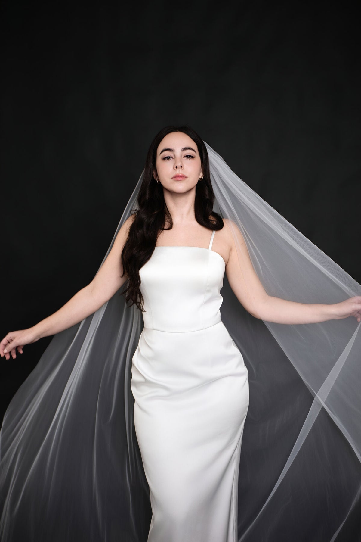 Bride holding The Barely There cathedral veil open with both arms extended, showing the width of the plain cut edge tulle