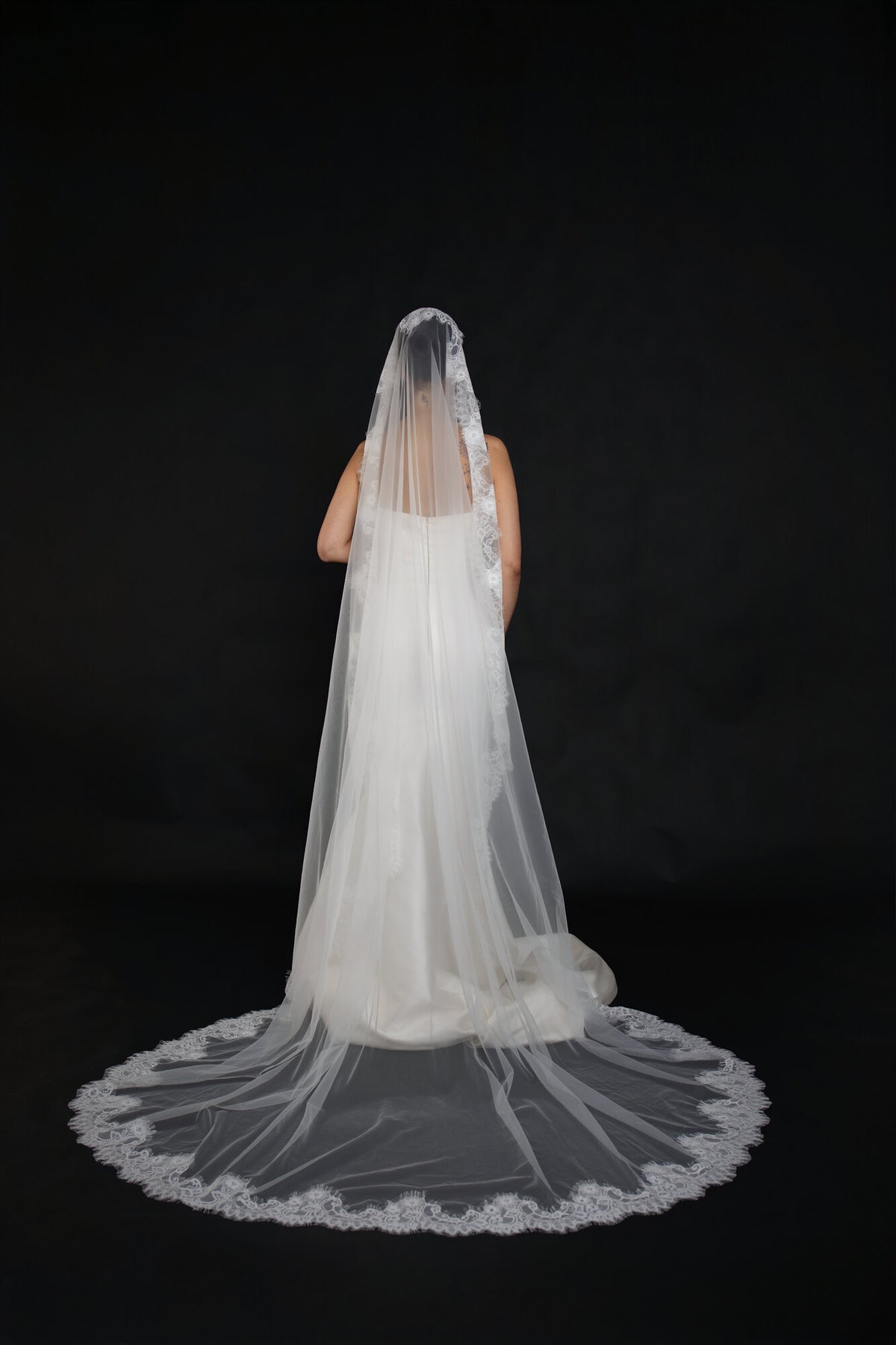 Back view of The Close Up mantilla veil fanned out on the floor, scalloped lace border visible around the entire hem