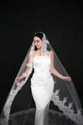 The Heirloom lace cathedral veil draped forward over both shoulders, lace border framing a fitted white gown