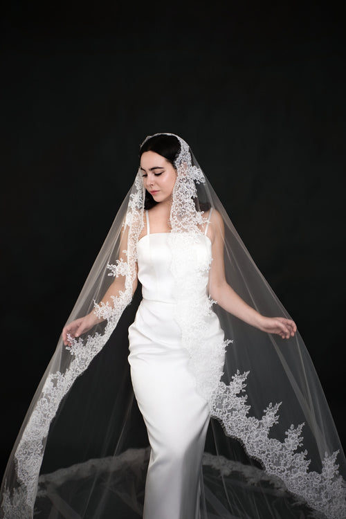 The Heirloom lace cathedral veil draped forward over both shoulders, lace border framing a fitted white gown