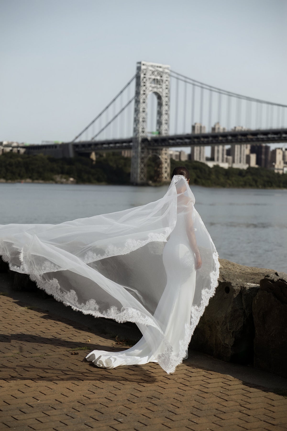 The Close Up mantilla veil caught in the wind by the water, with the George Washington Bridge behind