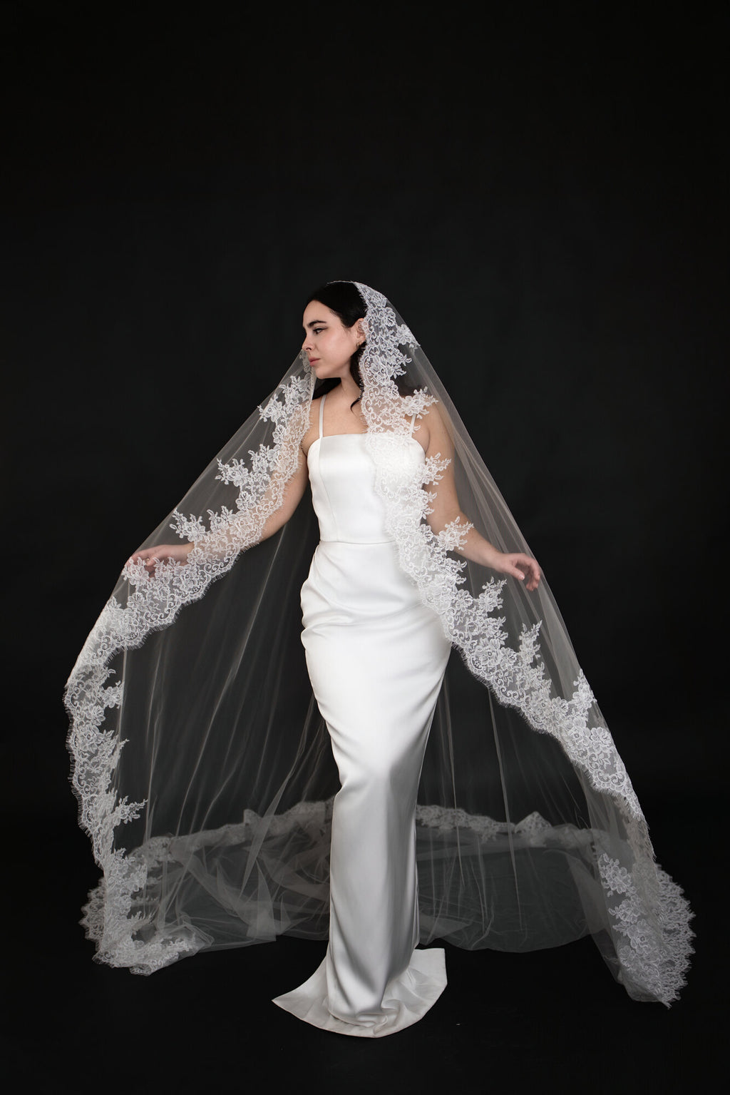 Bride holding The Heirloom lace cathedral veil open at both sides, showing the full span of the scalloped border