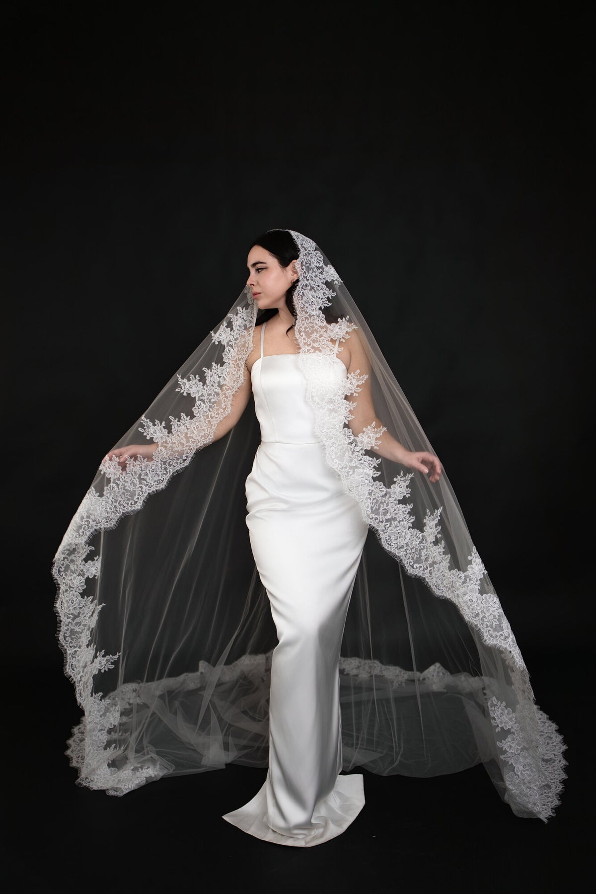 Bride holding The Heirloom lace cathedral veil open at both sides, showing the full span of the scalloped border