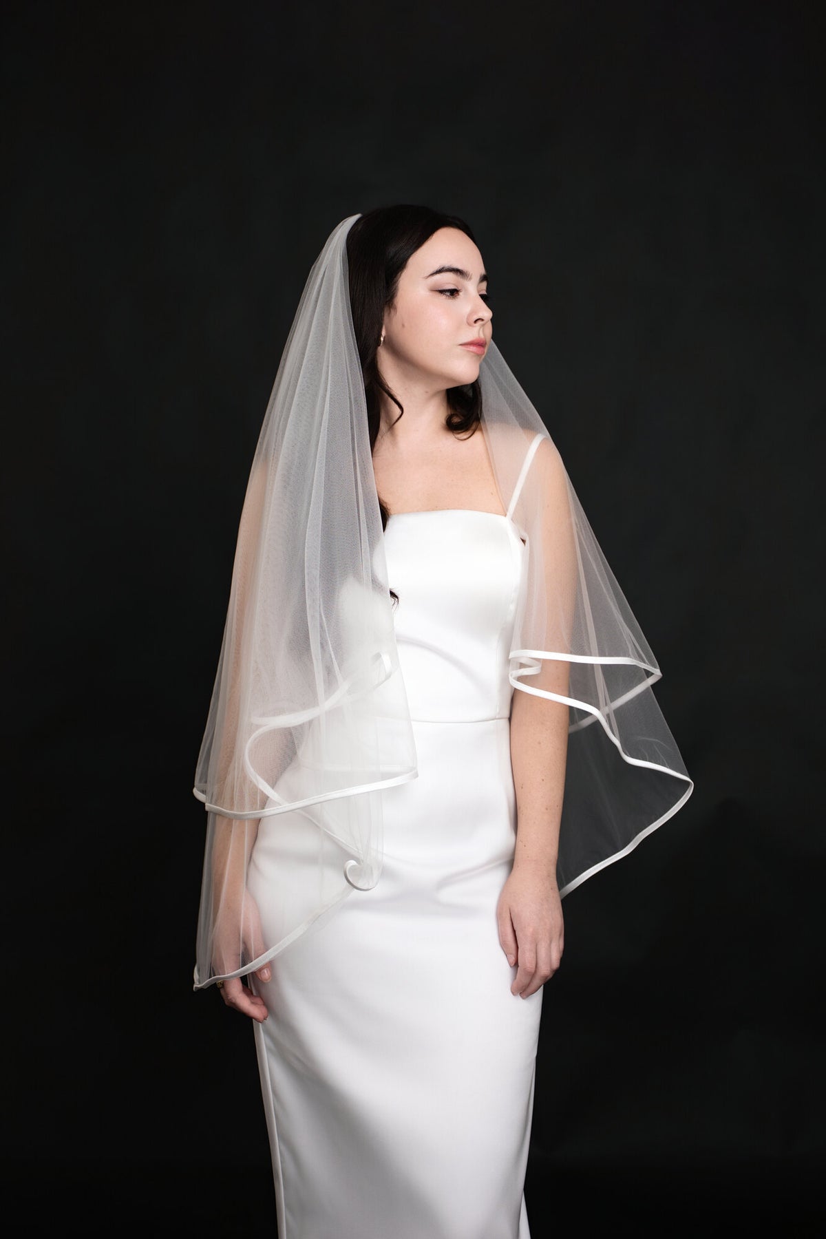 The Clean Line fingertip veil with the blusher back, worn over a white satin gown with thin straps