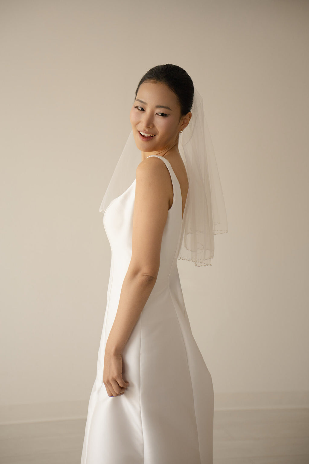 Profile view of The Second Look shoulder length pearl veil over a white slip gown