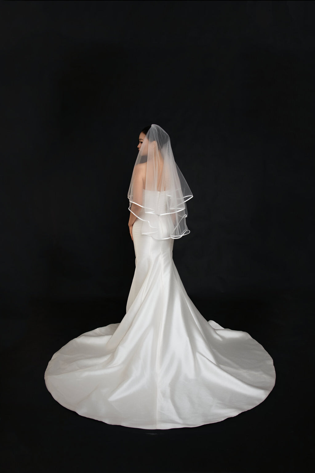 Full back view of The Clean Line two tier fingertip veil above the train of a white satin gown