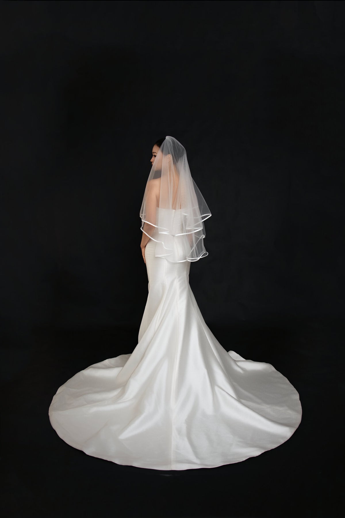 Full back view of The Clean Line two tier fingertip veil above the train of a white satin gown